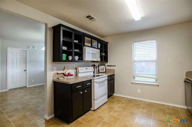 3903 Kevin Shaw Dr, Killeen, TX 76549 - kitchen featuring white appliances, dark cabinetry, a textured ceiling, light countertops, and glass insert cabinets
