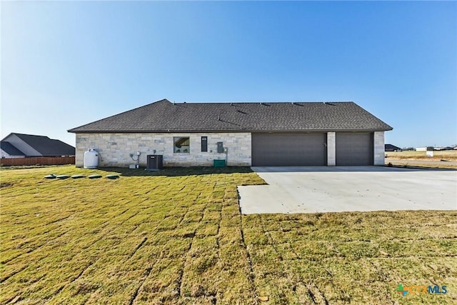 rear view of house featuring a garage, cooling unit, and a lawn