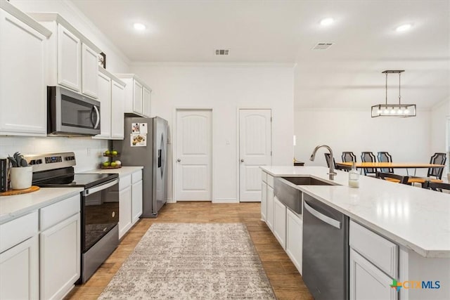 2619 Settlers Oak Dr, Belton, TX 76513 - kitchen featuring a center island with sink, stainless steel appliances, visible vents, light wood-style floors, and decorative backsplash