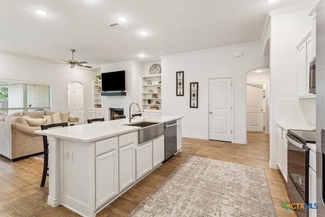 2619 Settlers Oak Dr, Belton, TX 76513 - kitchen with a brick fireplace, stainless steel appliances, a ceiling fan, arched walkways, and a sink