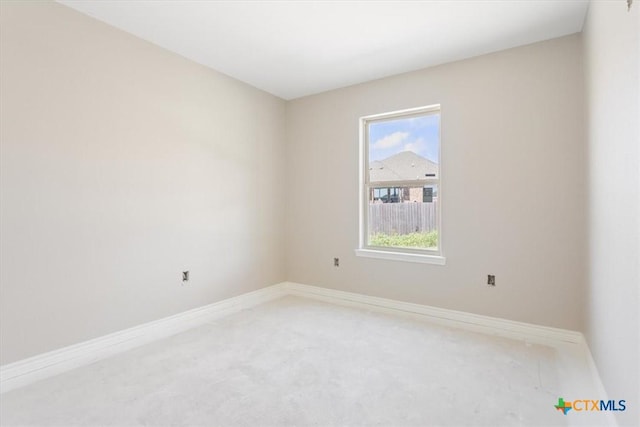 empty room featuring light colored carpet, a wealth of natural light, and baseboards