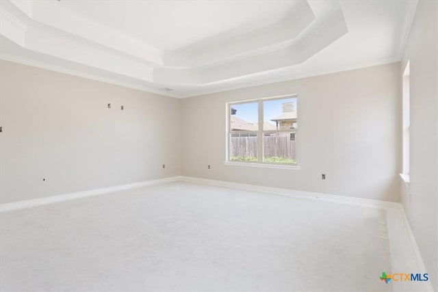 spare room featuring baseboards, a tray ceiling, carpet flooring, and crown molding