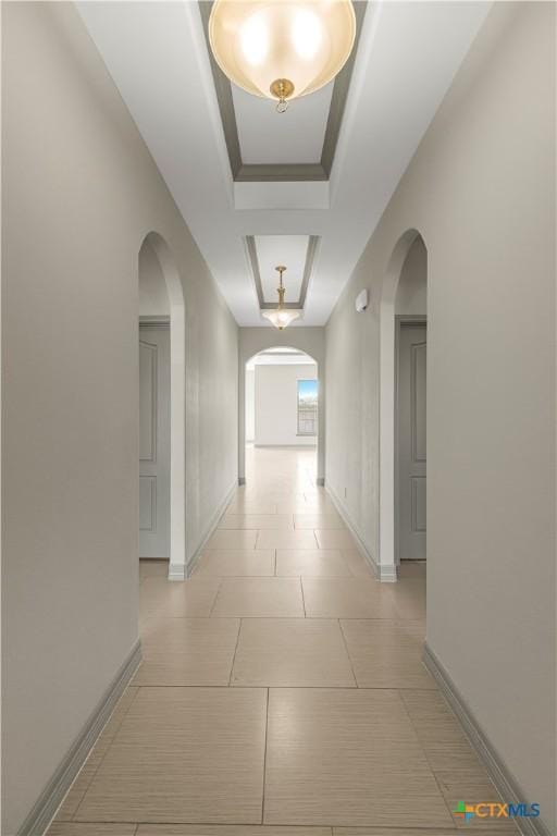 hall featuring light tile patterned floors and a tray ceiling