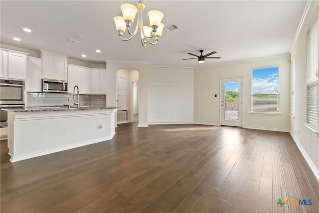 kitchen featuring stone countertops, appliances with stainless steel finishes, white cabinets, crown molding, and dark wood-type flooring