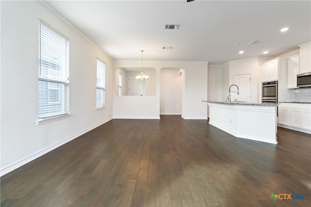 unfurnished living room featuring dark wood-type flooring, sink, crown molding, and an inviting chandelier