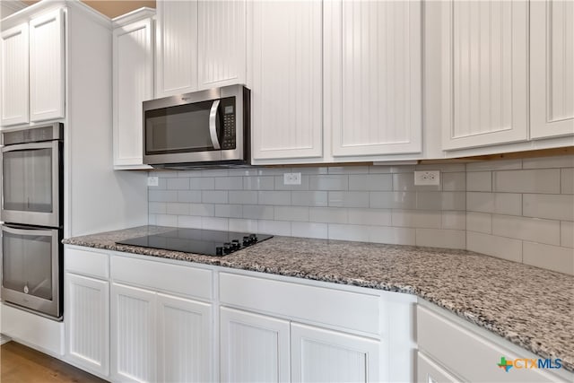 kitchen with white cabinetry, appliances with stainless steel finishes, tasteful backsplash, and light stone countertops