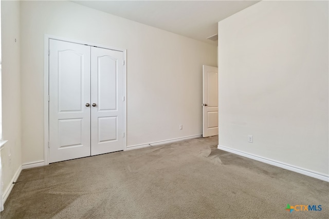 unfurnished bedroom with light colored carpet and a closet