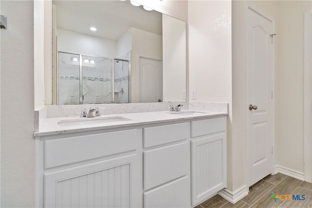 bathroom with hardwood / wood-style floors, vanity, and a shower with shower door