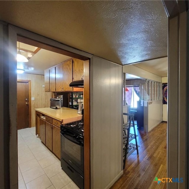 706 S 1st St, Copperas Cove, TX 76522 - kitchen featuring black gas stove, under cabinet range hood, light countertops, light wood-style floors, and a textured ceiling