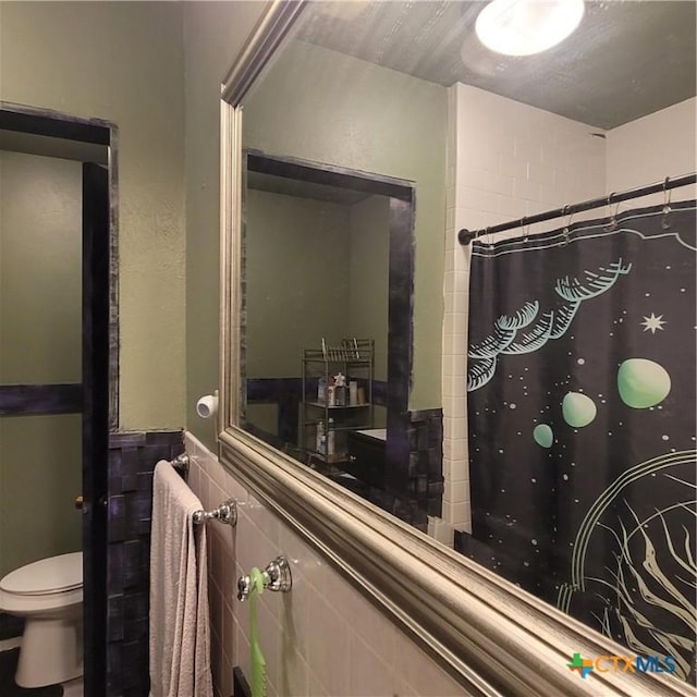 706 S 1st St, Copperas Cove, TX 76522 - bathroom featuring toilet, a shower with shower curtain, a wainscoted wall, and tile walls
