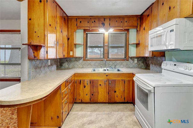 kitchen featuring sink, white appliances, kitchen peninsula, and backsplash