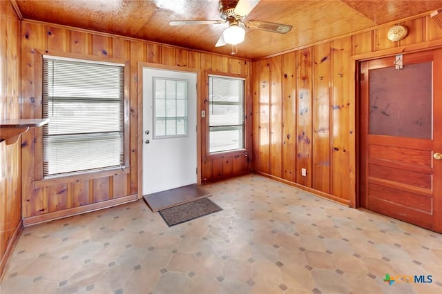 doorway to outside featuring wooden ceiling, ceiling fan, and wood walls