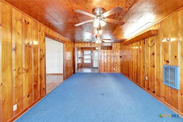 carpeted empty room with ceiling fan, wooden walls, heating unit, and wooden ceiling