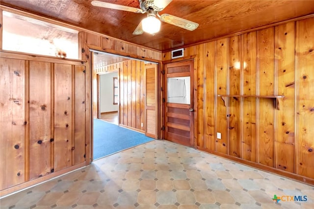 empty room featuring light tile patterned floors, wooden walls, wooden ceiling, and ceiling fan