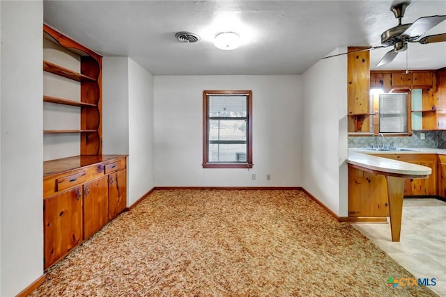 kitchen featuring sink, ceiling fan, backsplash, light carpet, and kitchen peninsula