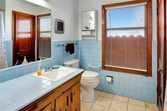 bathroom with heating unit, tile walls, vanity, toilet, and tile patterned floors