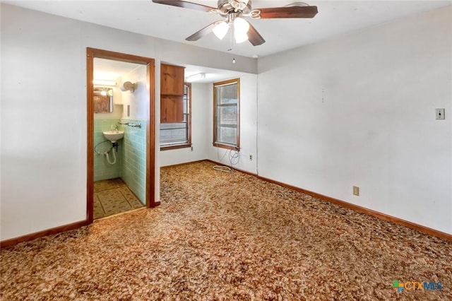 unfurnished bedroom with ceiling fan, ensuite bathroom, and carpet floors