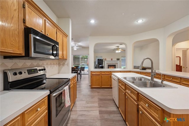 104 Missouri Dr, Harker Heights, TX 76548 - kitchen featuring stainless steel appliances, a ceiling fan, a sink, light wood-style floors, and a warm lit fireplace