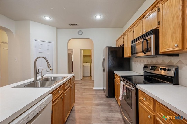 104 Missouri Dr, Harker Heights, TX 76548 - kitchen featuring appliances with stainless steel finishes, arched walkways, washer / clothes dryer, a sink, and light wood-type flooring