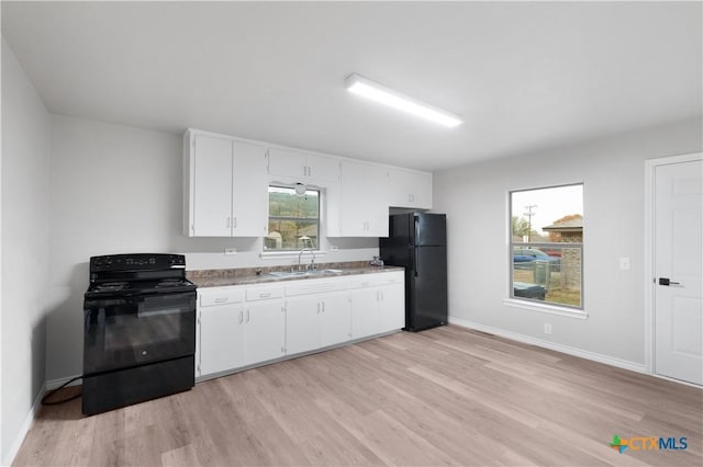 kitchen featuring white cabinetry, sink, black appliances, and light wood-type flooring