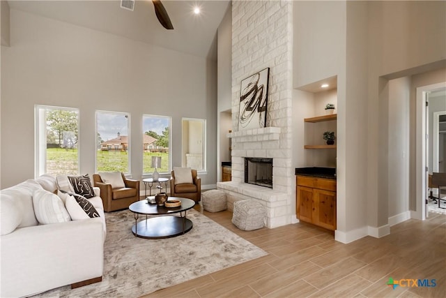 104 Hondo Vis, La Vernia, TX 78121 - living room featuring high vaulted ceiling, a large fireplace, a ceiling fan, and light wood-type flooring