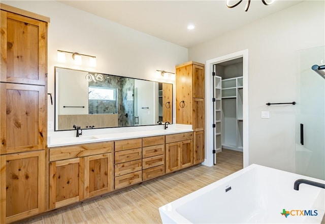 bathroom featuring vanity, wood-type flooring, and a tub to relax in