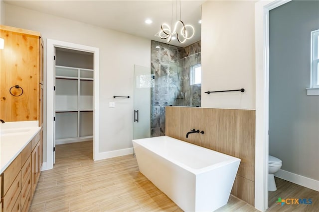 full bathroom with vanity, hardwood / wood-style flooring, a chandelier, shower with separate bathtub, and toilet