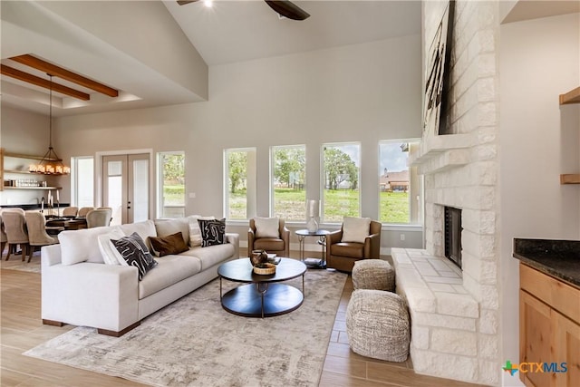 104 Hondo Vis, La Vernia, TX 78121 - living room with a high ceiling, light wood-style floors, ceiling fan, a stone fireplace, and healthy amount of natural light