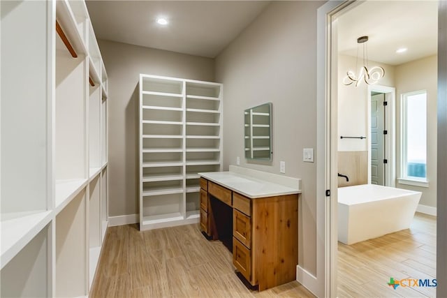 spacious closet with a chandelier and light hardwood / wood-style floors