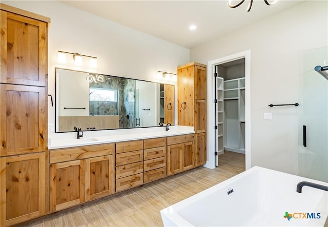 104 Hondo Vis, La Vernia, TX 78121 - bathroom with double vanity, a soaking tub, a spacious closet, and an enclosed shower