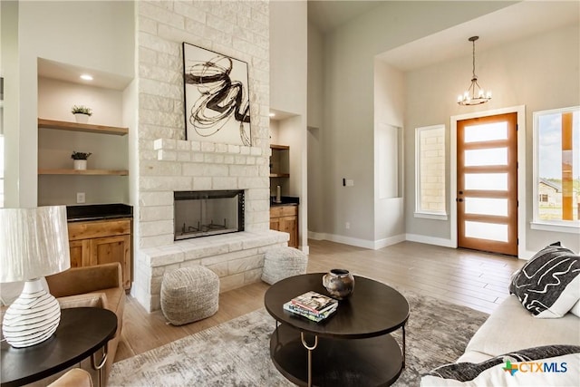 104 Hondo Vis, La Vernia, TX 78121 - living area with light wood-style flooring, a chandelier, built in features, a fireplace, and a towering ceiling