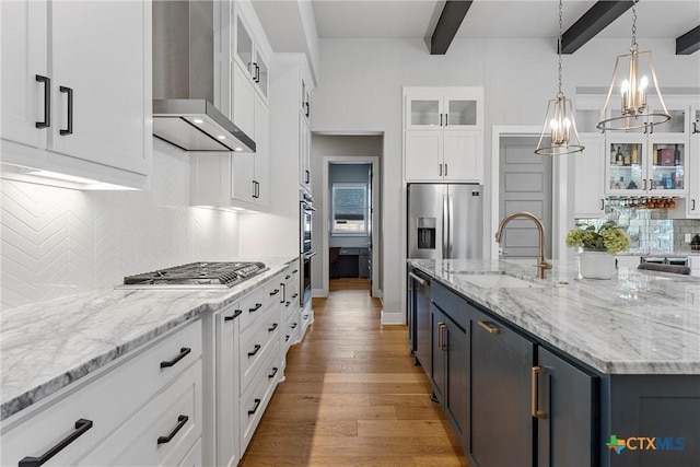 kitchen with sink, white cabinetry, beamed ceiling, and wall chimney exhaust hood