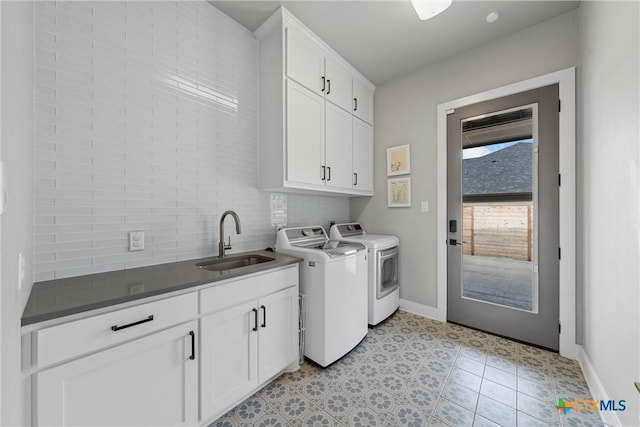 clothes washing area with cabinets, light tile patterned floors, washer and clothes dryer, and sink