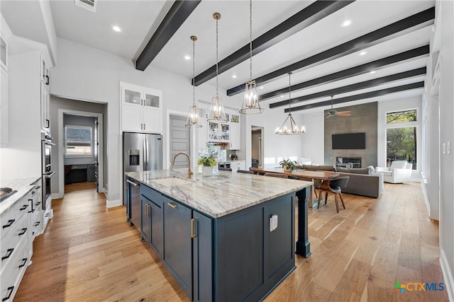 kitchen featuring a large island, hanging light fixtures, beam ceiling, sink, and white cabinetry