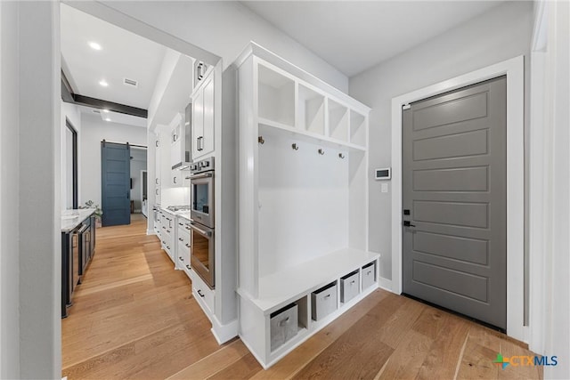 mudroom featuring a barn door and light hardwood / wood-style floors