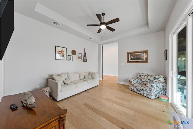 living room featuring ceiling fan, a raised ceiling, and hardwood / wood-style flooring