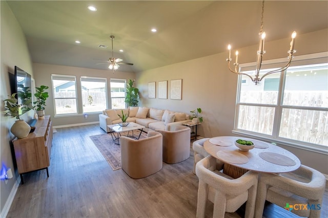 living area with lofted ceiling, ceiling fan with notable chandelier, wood finished floors, recessed lighting, and baseboards