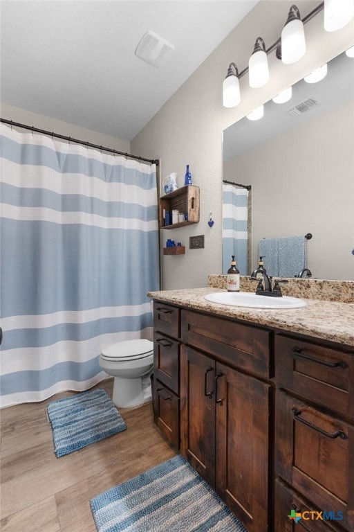 bathroom with visible vents, toilet, vanity, and wood finished floors