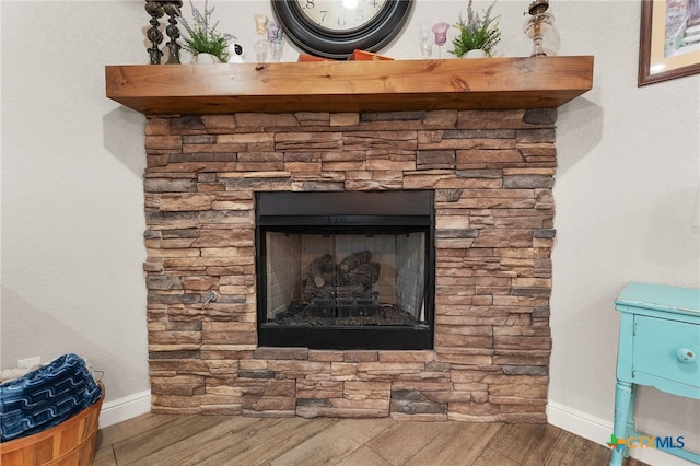 room details with a stone fireplace, baseboards, and wood finished floors