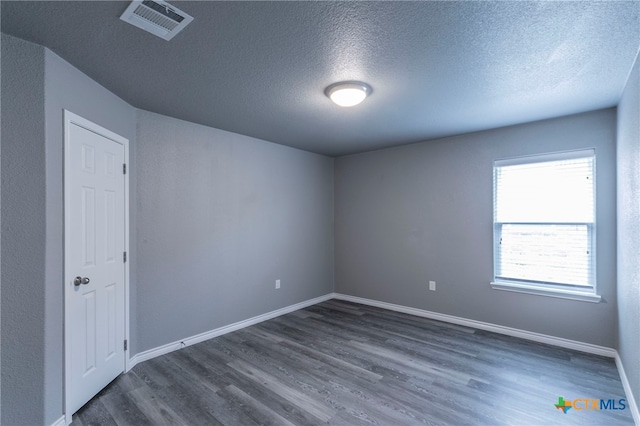 spare room with dark wood-type flooring and a textured ceiling