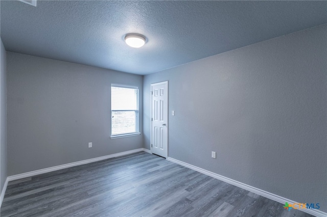 spare room featuring a textured ceiling and dark hardwood / wood-style floors