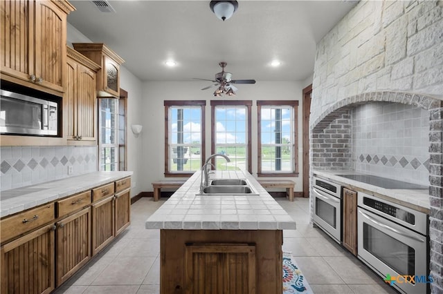 12491 Madison Ln, Justin, TX 76247 - kitchen featuring stainless steel appliances, a sink, an island with sink, light tile patterned floors, and recessed lighting