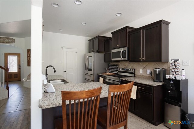 3608 Quail Ridge Dr, Harker Heights, TX 76548 - kitchen with appliances with stainless steel finishes, a sink, light tile patterned flooring, backsplash, and dark brown cabinetry