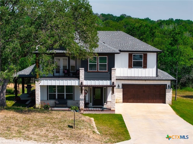 127 Diamond Head Dr, Bastrop, TX 78602 - view of front of property featuring a balcony, a shingled roof, concrete driveway, an attached garage, and stone siding