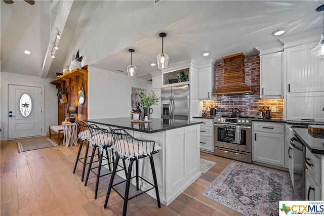 kitchen with stainless steel appliances, a center island, pendant lighting, white cabinetry, and premium range hood