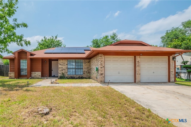 ranch-style house with solar panels, a front yard, and a garage