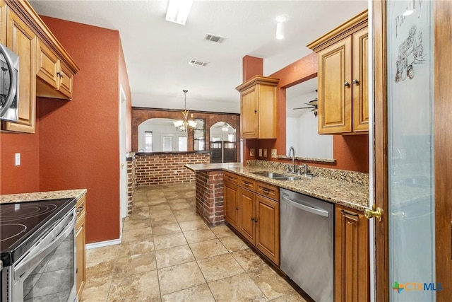 kitchen with light stone countertops, visible vents, arched walkways, a sink, and appliances with stainless steel finishes