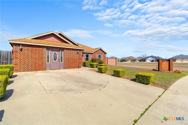 view of front of house featuring a front lawn, fence, and brick siding