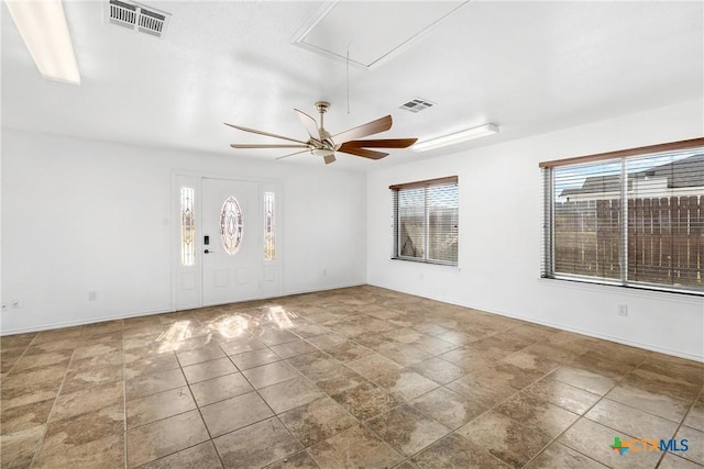 unfurnished room with visible vents, baseboards, attic access, and ceiling fan