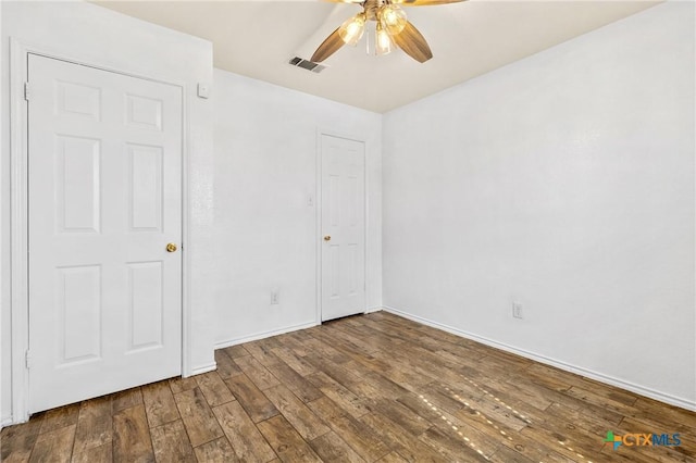 unfurnished bedroom with visible vents, ceiling fan, baseboards, and wood finished floors